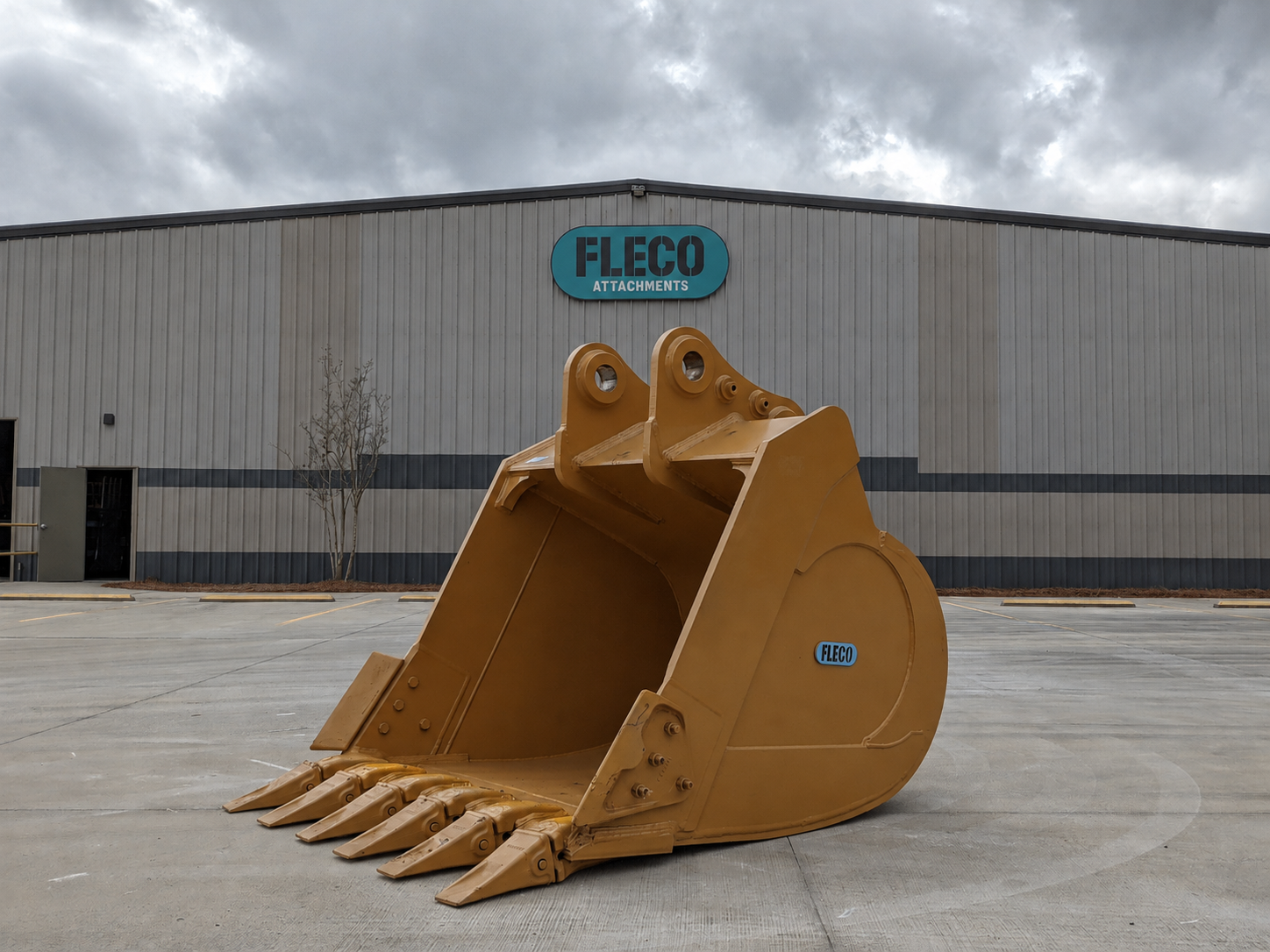 Large excavator bucket in front of the FLECO Attachments facility