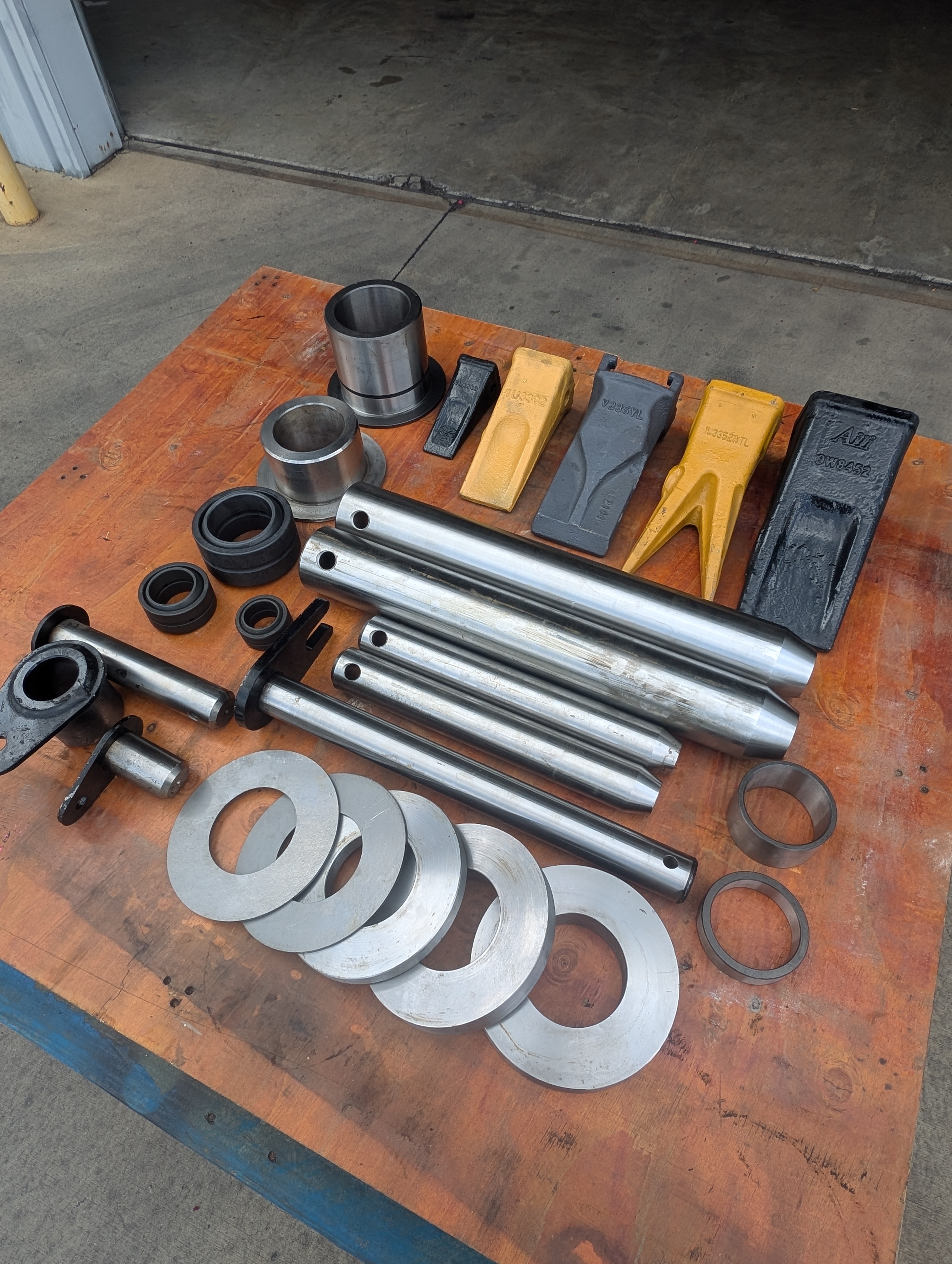 FLECO teeth, pins, bushings, and shims arranged on a workbench in the FLECO shop