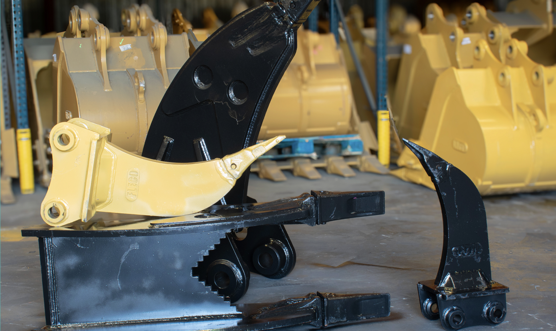 FLECO excavator ripper and stumper attachments in yellow and black in the FLECO yard