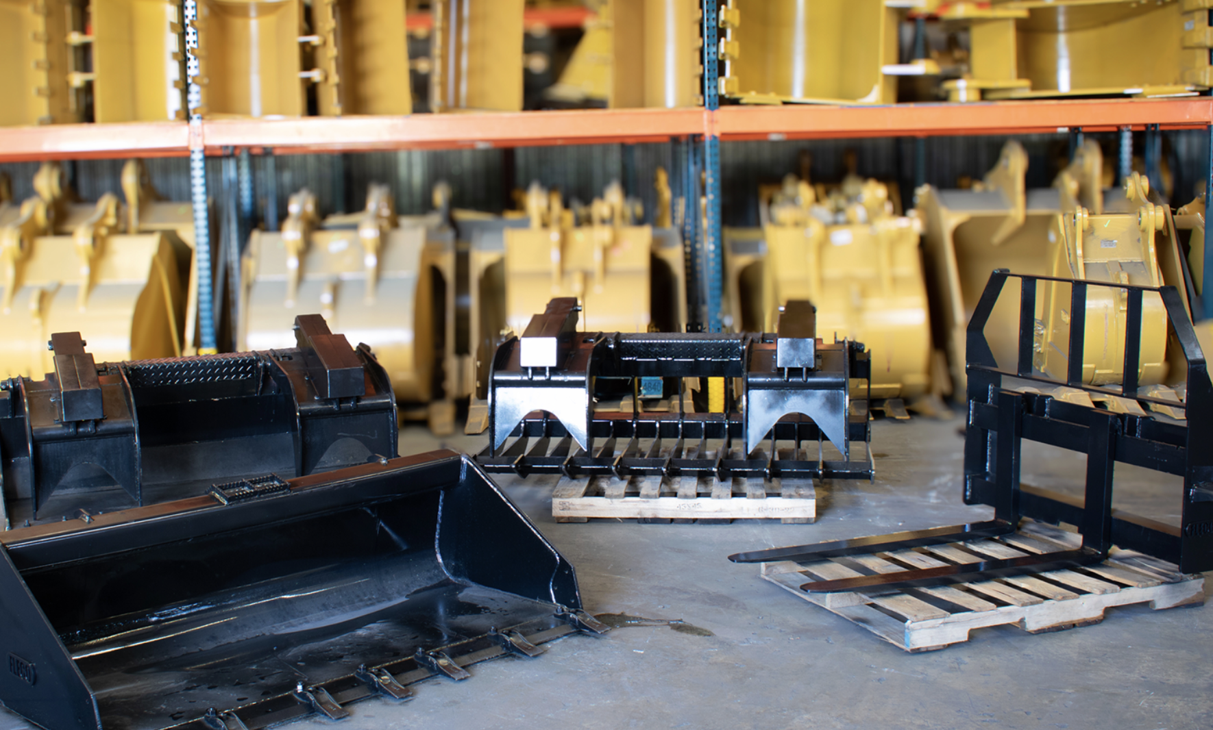 FLECO skid steer attachments staged on pallets in the FLECO warehouse