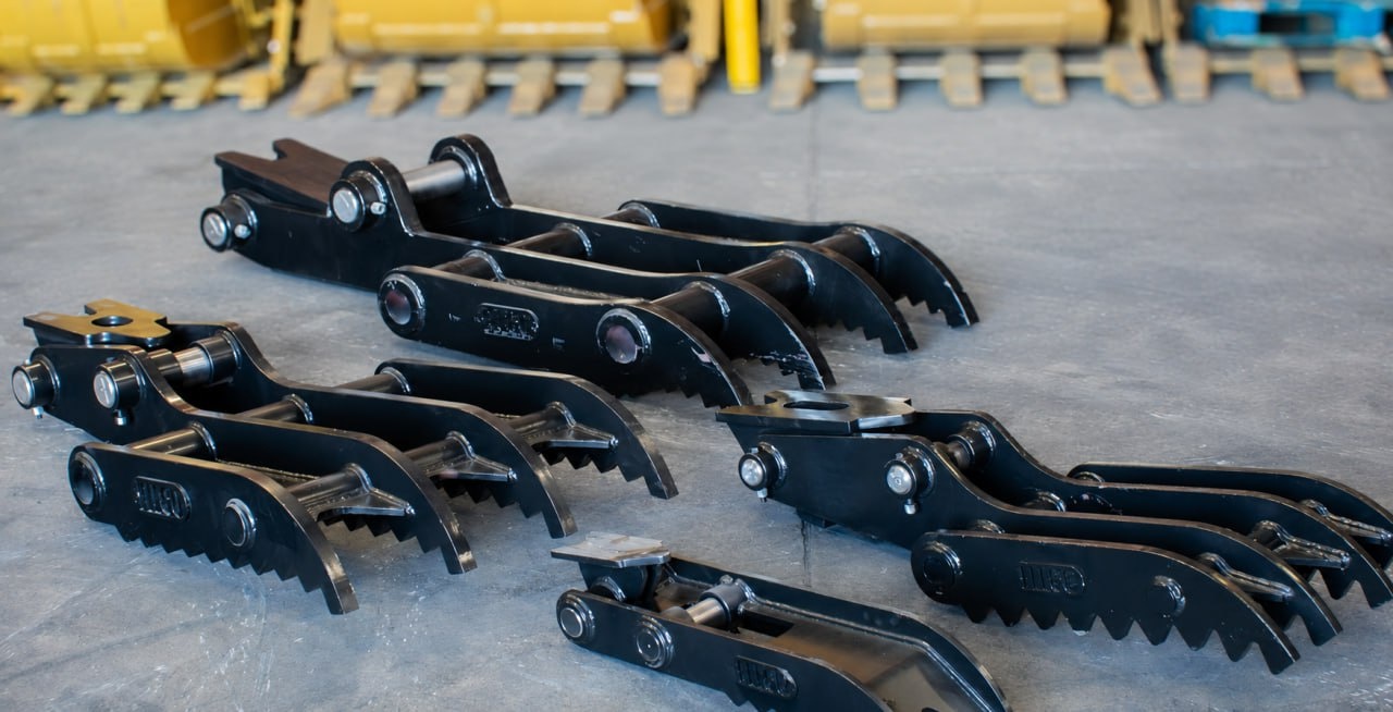 A lineup of black FLECO excavator thumbs staged on the shop floor
